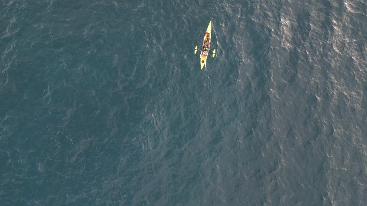 vista aérea de drones de arriba hacia abajo de un kayak de pesca amarillo en el océano pacífico