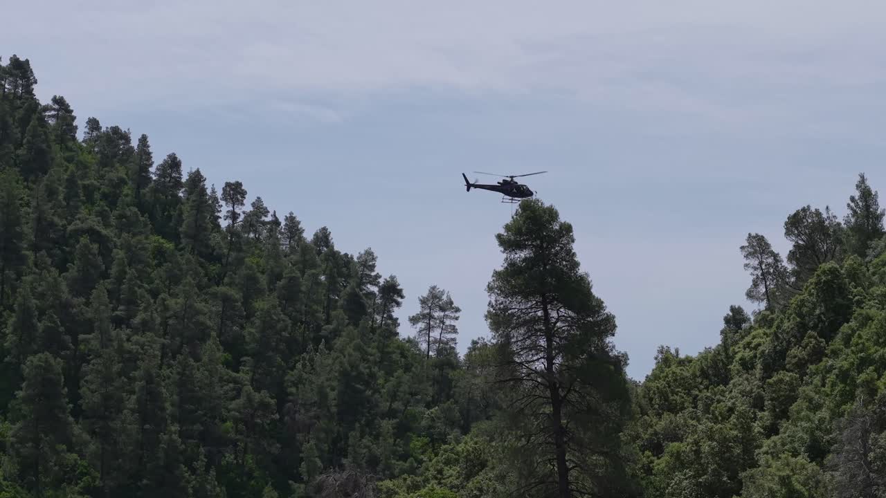 A helicopter delivers construction materials for wire mesh installation to prevent landslides in a remote and steep terrain. Aerial logistics in action.