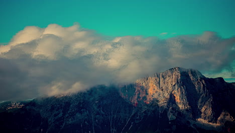 swift clouds streaming over an austrian mountain peak at sunset