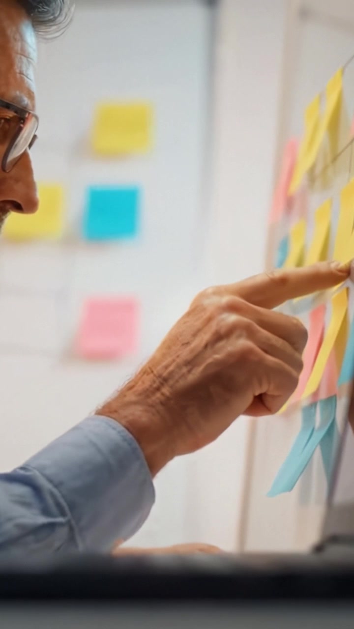 A close-up view of a hand interacting with sticky notes on a board while working on a collaborative project, illustrating teamwork and creative brainstorming.