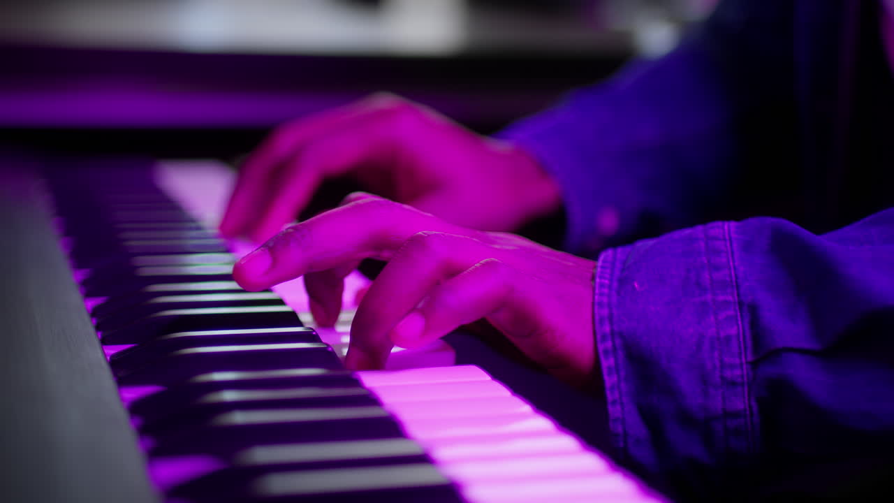 Close-up of Hands Playing Piano Keyboard Under Purple Light