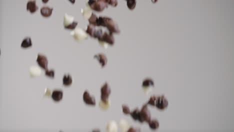 chips de leche, chocolate blanco y oscuro lloviendo en cámara lenta 4k con fondo gris