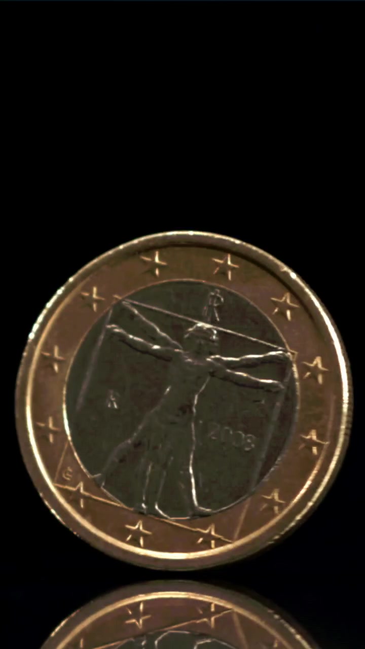 Moneta da un euro che gira su una superficie nera riflettente