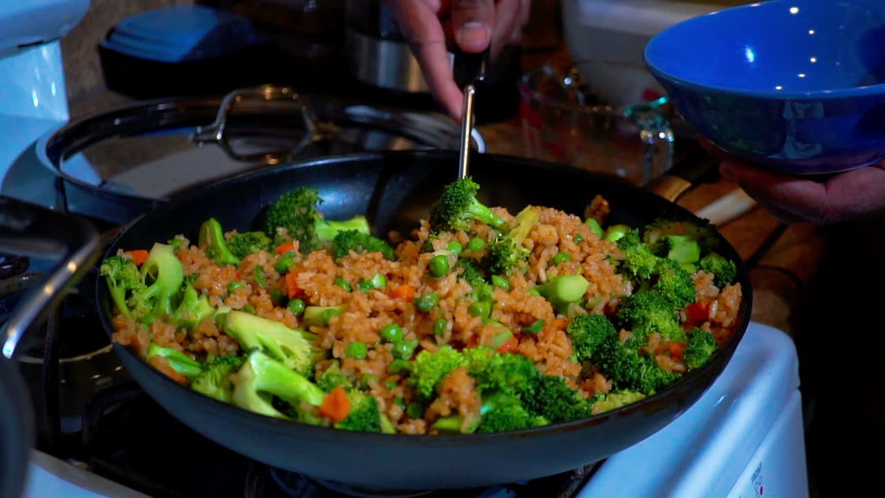 Serving vegetable stir fried rice into blue bowl, Slow Motion Closeup