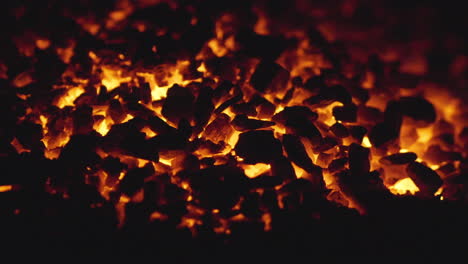 Fiery-coals-in-dark-stove,-nighttime-heat-source-close-up