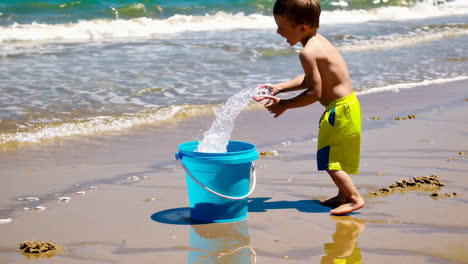 a young boy playing with a bucket on a sandy beach
