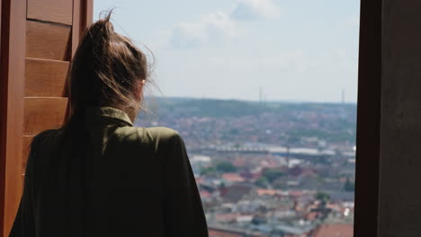 woman looking at cityscape through a window