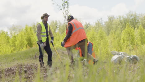 grupo de activistas ecologistas multiétnicos arando la tierra y plantando árboles en el bosque
