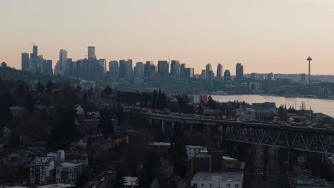 traffic flows across a bridge in the evening golden hour with the downtown seattle skyline and space needle by lake union in the background