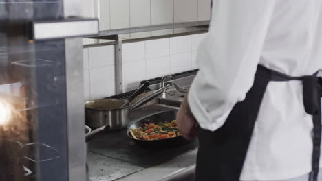 chef caucásico fritando verduras en la cocina, en cámara lenta