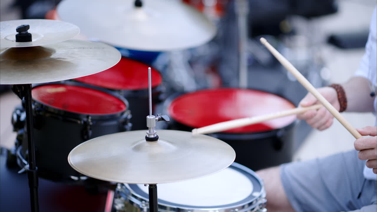 Close up of man playing red drums outside