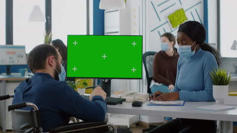 gerente con máscara facial escribiendo en la pc con pantalla verde discutiendo con un empleado africano