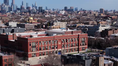 cinematic establishing drone shot of urban brick school in dense american city