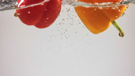 red and yellow bell peppers falling into water