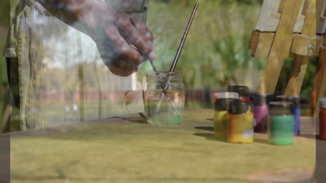 dipping paintbrush into jar, hands preparing for animation on outdoor table