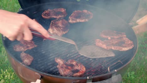 rebanadas de jugosa carne de cerdo a la parrilla movidas con espátula en la parrilla de carbón