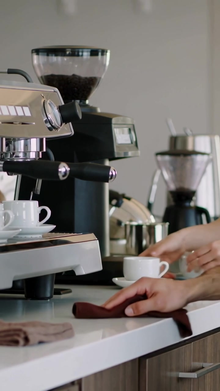 Video verticale: Barista che pulisce e impila tazze al bar, preparando il servizio con caffè espresso, con spazio per il testo.