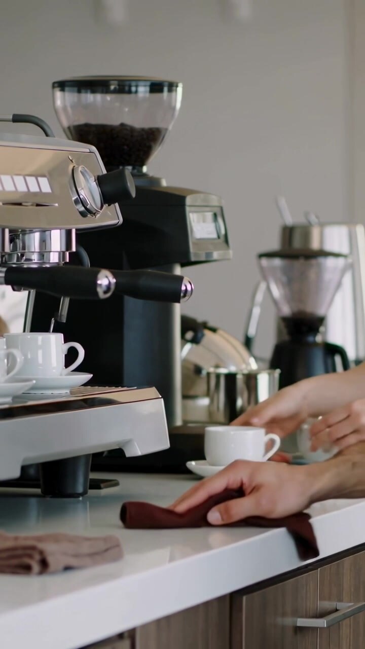 Video verticale: Barista che pulisce e impila tazze al bar, preparando il servizio con caffè espresso, con spazio per il testo.