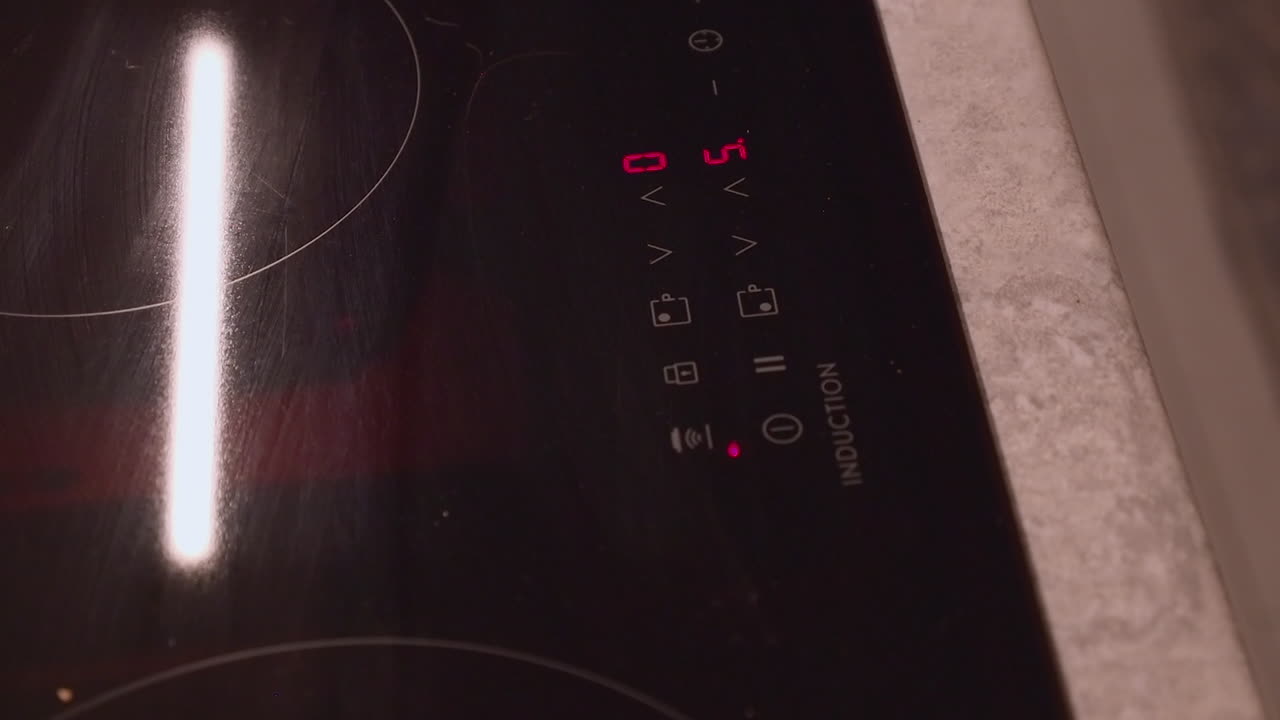Index finger on right hand adjusts settings on induction cooktop stove