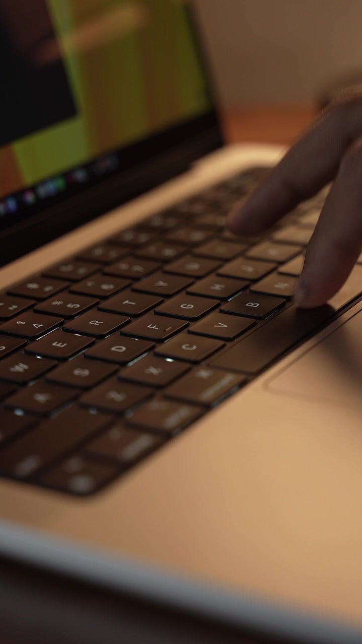 Mani che digitano sulla tastiera del laptop in una stanza calda, accogliente e illuminata