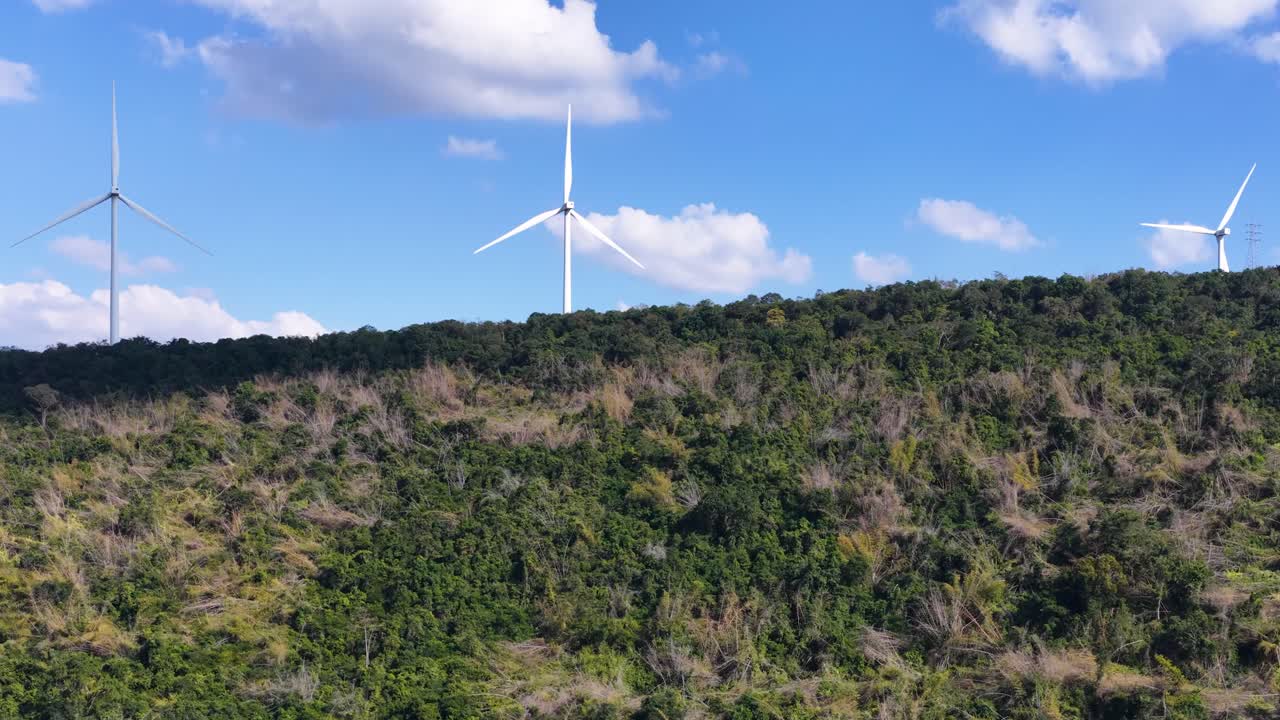 Plano geral estático de turbinas eólicas brancas gerando energia renovável no topo de uma montanha florestal