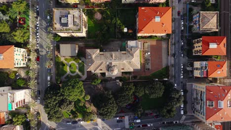 a residential area in italy with green parks, roads, and rooftops, aerial view