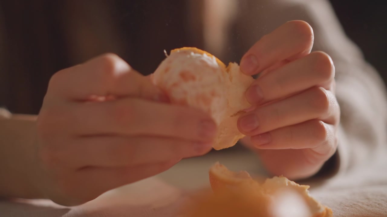 Closeup of fingers peeling orange rind carefully. Detailed view of fingertips delicately removing bright orange peel. Close examination of hands gently stripping vibrant citrus peel from fruit
