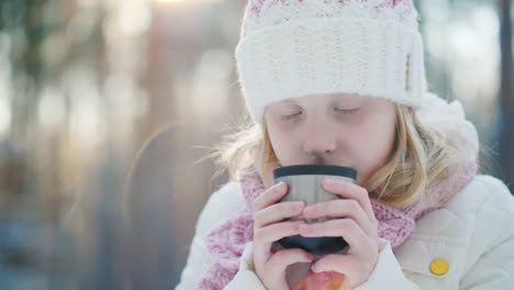 Ein-6-jähriges-Mädchen-Trinkt-Heißen-Tee-Auf-Der-Straße-Vor-Dem-Hintergrund-Der-Winterwald-Slow-Moti