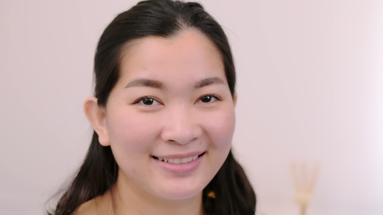 아름답고 웃고 있는 아시아 여성들은 휴일에 혼자 전문적인 초상화를 취한 카메라를 바라보며 극도로 자신감 있는 젊은 얼굴을 하고 맑은 빛, 슬로우 모션 장면으로 휴식을 취합니다.