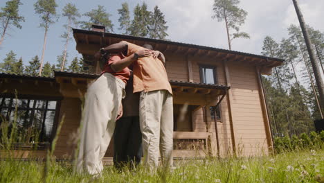 widok z dołu szczęśliwej rodziny rozmawiającej i przytulającej się przed domem w słoneczny poranek