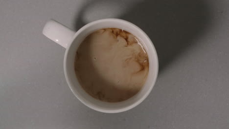 pouring milk or half and half into a fresh cup of dark coffee, birds eye view, slow motion, 4k