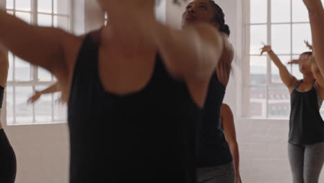 beautiful african american yoga woman practicing warrior pose meditation with group of multiracial women enjoying healthy lifestyle exercising in fitness studio at sunrise