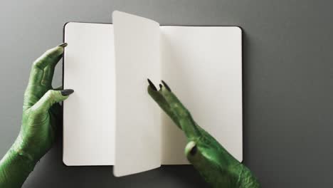 video of halloween green monster hands and notebook with copy space on grey background