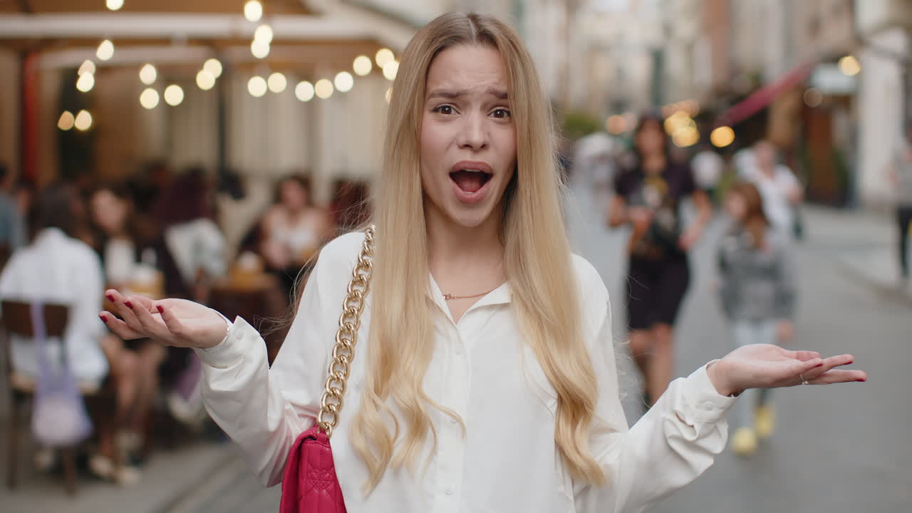 Surprised frustrated young woman raising hands asking reason of failure demonstrating disbelief