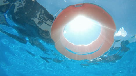 life belt or life preserver floating on top of sunny blue water, slow motion, underwater view