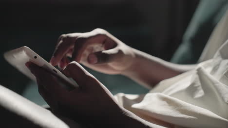 black youth in white shirt holding tablet in hands, using touchscreen with fingers, focused on device, in dimly lit room with dark background, engaging with technology, modern lifestyle
