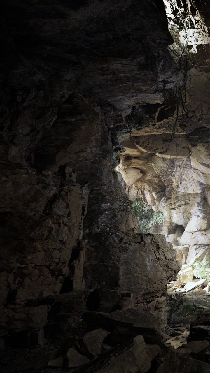 La luce illumina una grotta buia, mostrando pareti rocciose e formazioni naturali.