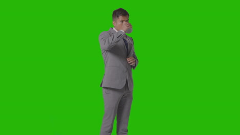 studio shot of businessman in suit holding and drinking cup of hot drink against green screen 3