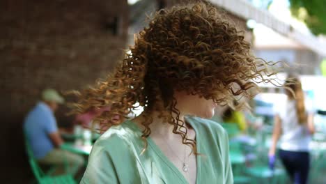 slow motion of a pretty ginger girl with professional pink makeup posing while smiling. she is having attractive look. wearing green blouse, twisting her head and laughing cheerfuly to the camera. outdoors