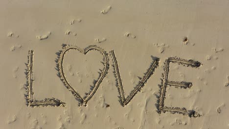 Aerial-camera-descending-on-LOVE-inscribed-in-the-sand-on-a-beach