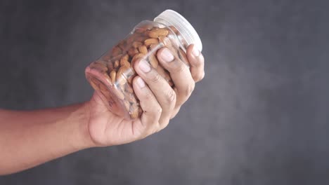 hand holding a jar of almonds