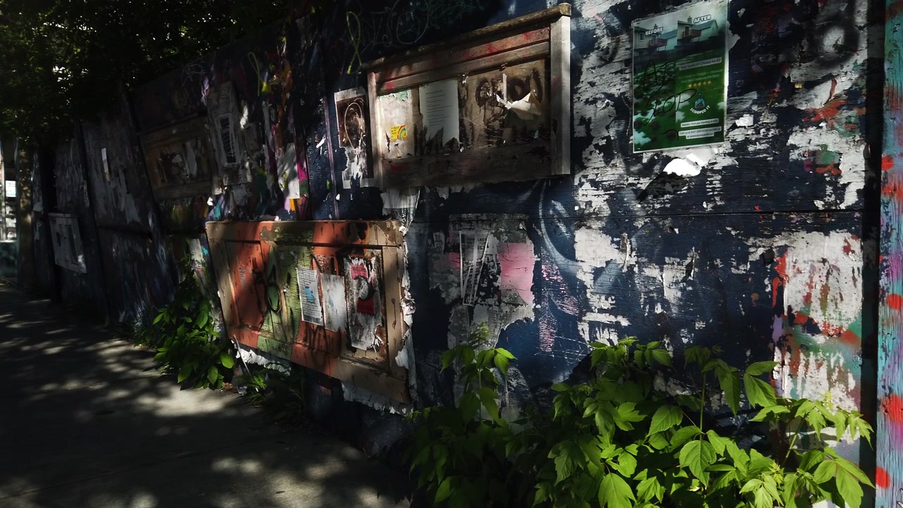 Un'alta parete di manifesti sbiaditi e usurati su Danforth Avenue a Toronto, inquadratura ampia con panoramica da sinistra a destra