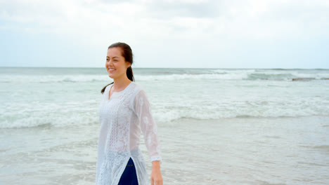 Front-view-of-young-caucasian-woman-standing-at-beach-on-a-sunny-day-4k-