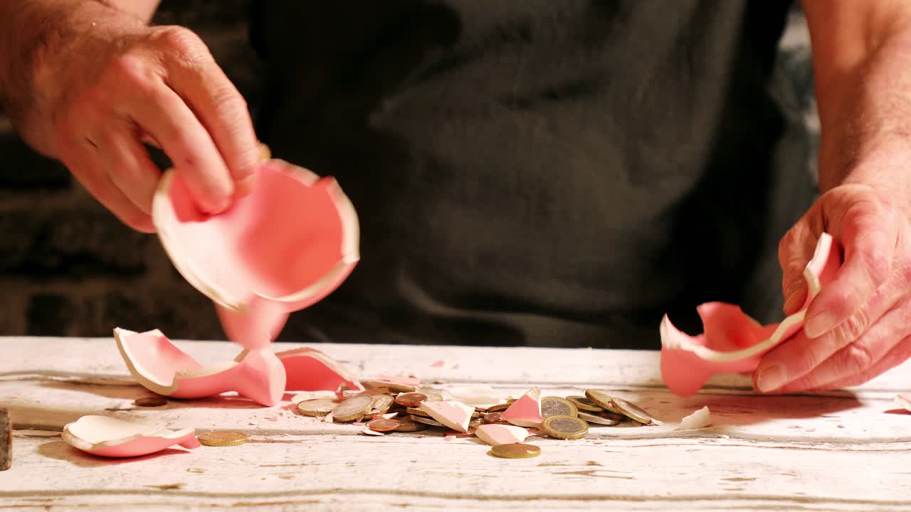 Breaking piggy bank with hammer, getting to the savings, financial concept