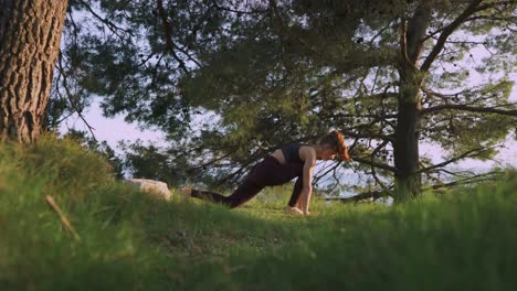 Outdoor-yoga,-young-woman-doing-sunrise-asana-flow-stretches-in-forest