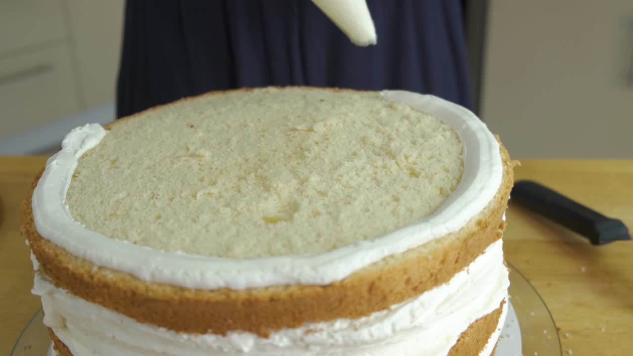 Nærbillede af kvindehænder, der laver sød kage med hvid creme og kiks.