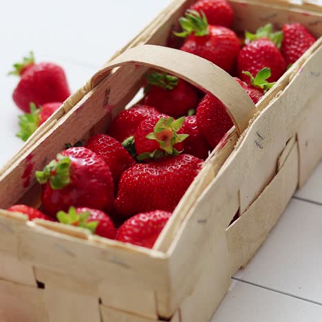 wooden container with fresh red strawberries  placed on white table