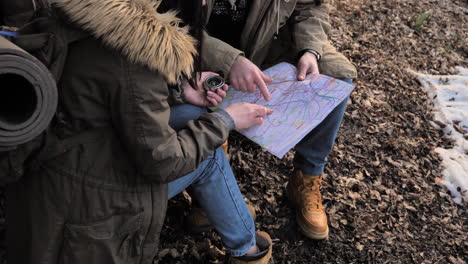 una pareja caucásica revisando el mapa en un bosque.