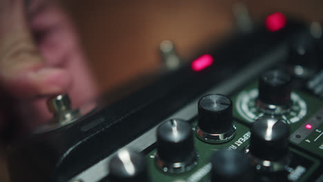 close-up of a person's hand pressing a button on a guitar effects pedal