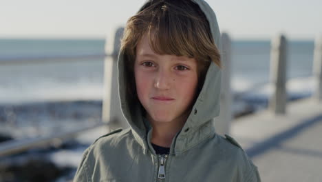 close up portrait happy little boy smiling cheerful enjoying vacation on beautiful sunny seaside wearing warm jacket slow motion